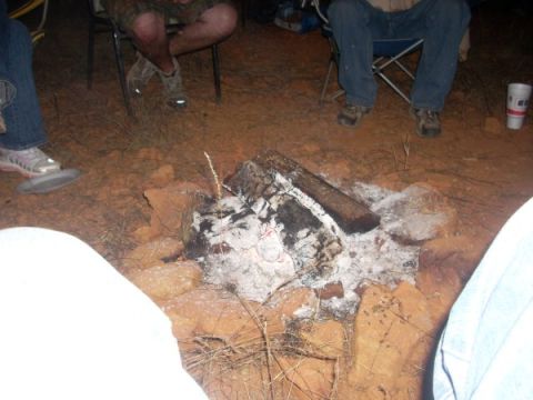 1992 Ford Bronco - A group of people gather around a campfire at dusk, with logs burning down to ash.