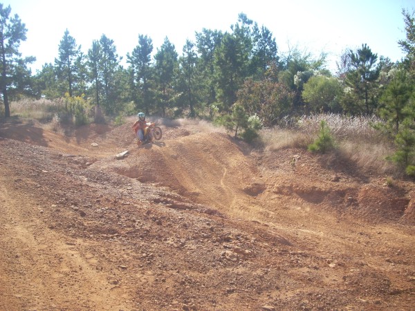 Dirt bike rider on a sandy hill with trees in the background