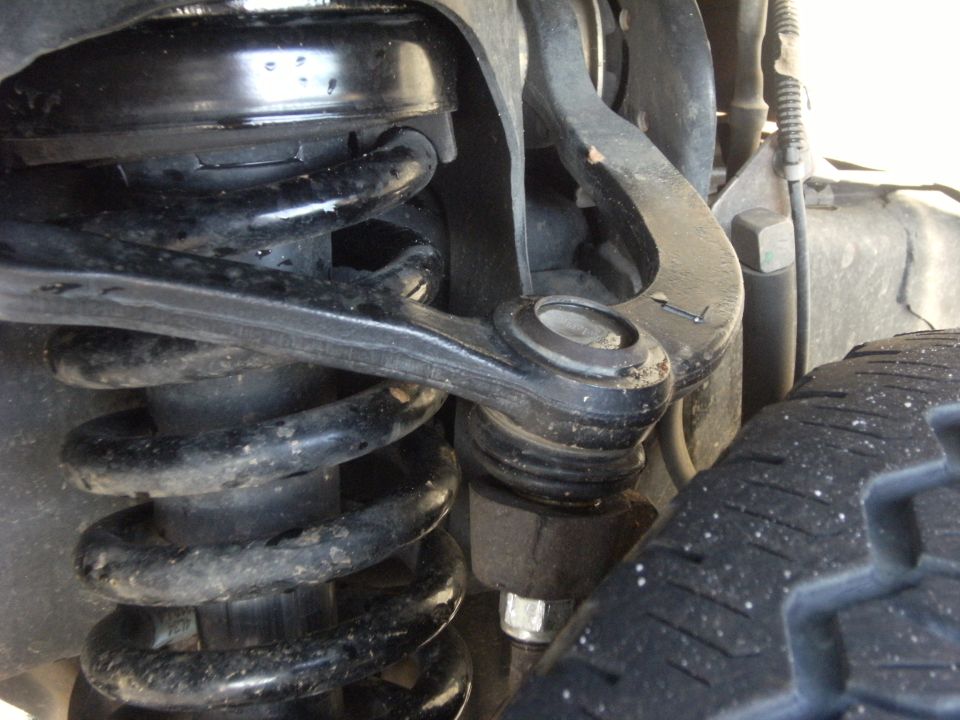 Close-up of front coil spring, control arm and ball joint suspension components