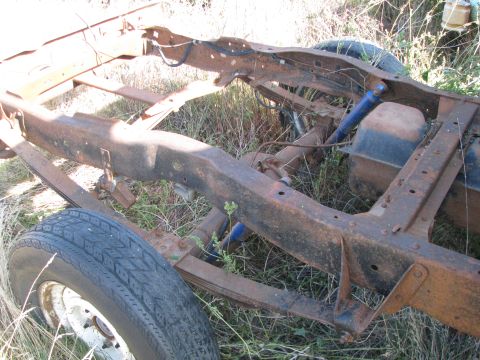 1983 Ford F-250 - The chassis of a heavily rusted truck is visible, with a single tire and fuel tank.