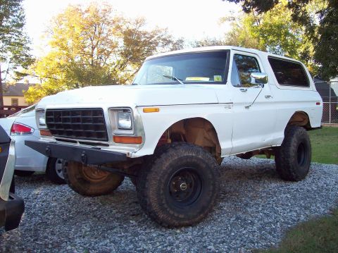 White Ford Bronco with aftermarket bumper and large tires, viewed from the front-left