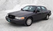 2003 Ford Crown Victoria - A dark 2003 Ford Crown Victoria sedan is seen from a three-quarter front view, parked outdoors in a snowy environment.