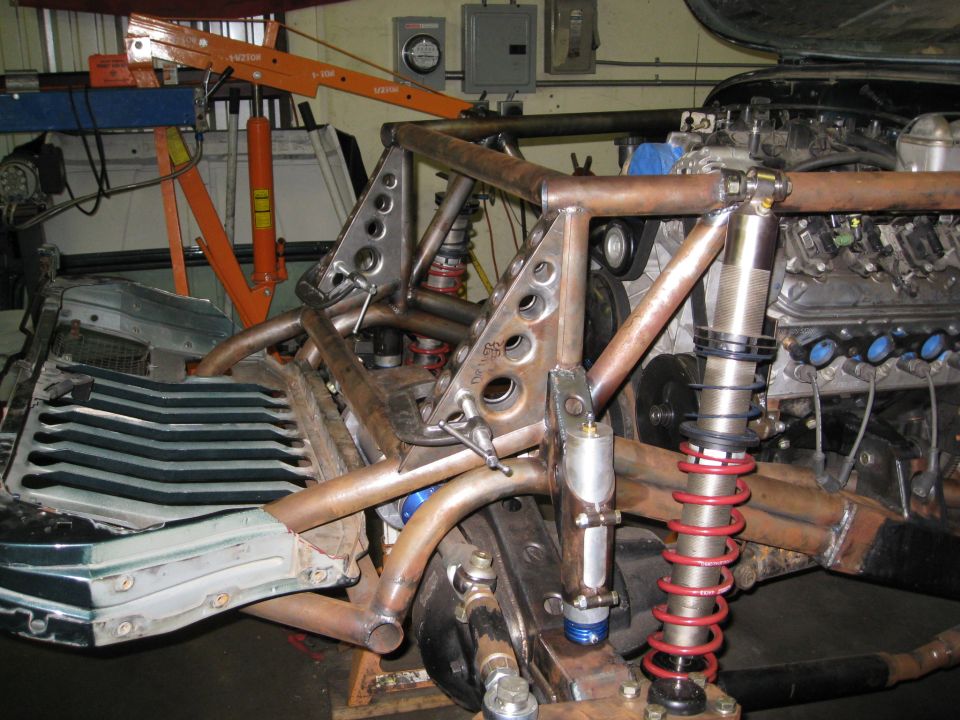 custom tube chassis with engine and suspension components, orange engine hoist in background