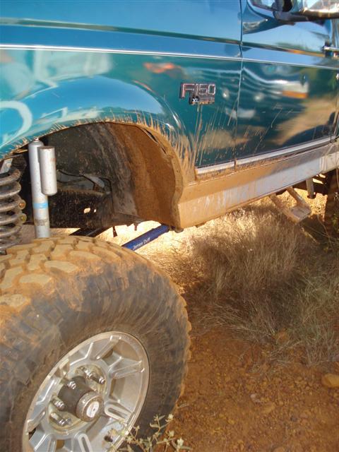 2008 International School Bus - Muddy fender and large tire on a green Ford F-150 truck.