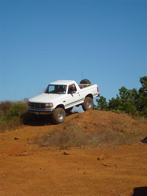 2008 International School Bus - A white pickup truck navigates an off-road course on a sunny day.