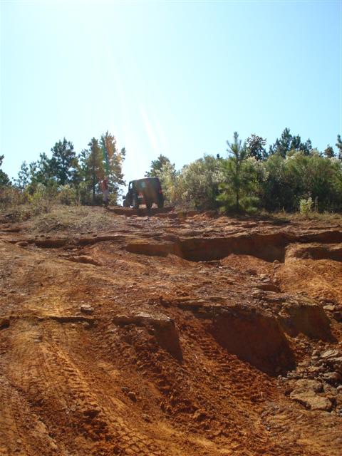2008 International School Bus - A vehicle navigates a challenging off-road trail with deep tire tracks in the red dirt.