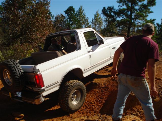 White Ford Bronco with spare tire on back, driving off-road