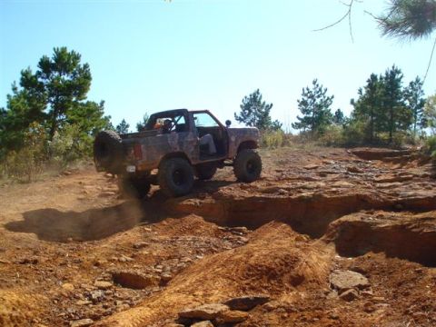 2008 International School Bus - A modified off-road vehicle navigates a challenging rocky trail under a clear blue sky.