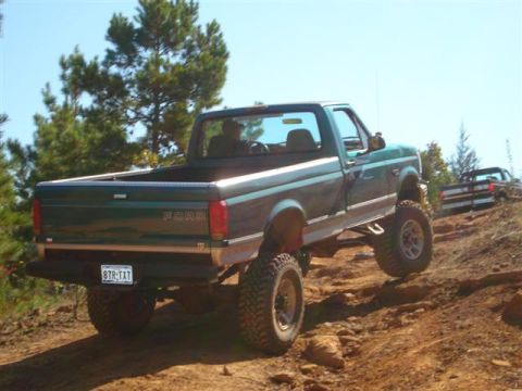 2008 International School Bus - Ford pickup truck navigates a steep, rocky off-road trail with another vehicle behind it.