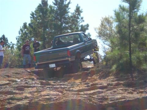 2008 International School Bus - A green pickup truck navigates a challenging rocky terrain during an off-road excursion.
