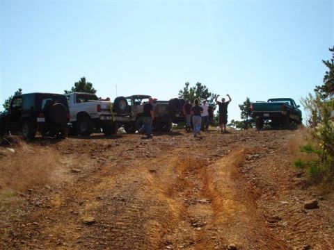 2008 International School Bus - A group of people and their off-road vehicles are gathered on a dusty trail under a clear blue sky.