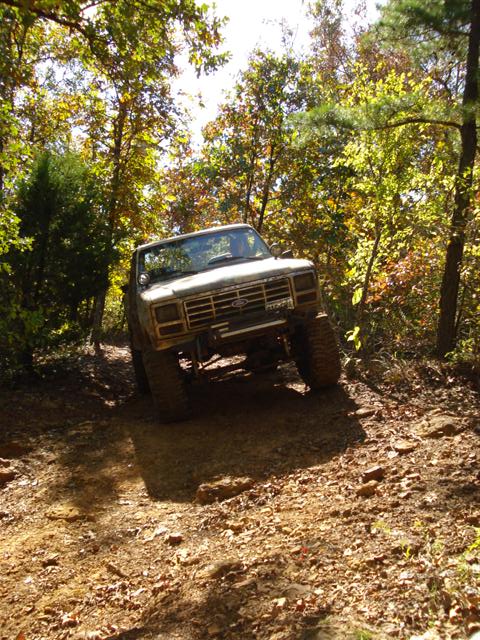 2008 International School Bus - Pickup truck navigating a challenging off-road trail in a wooded area.
