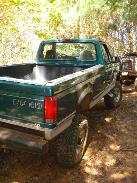 2008 International School Bus - A green Ford pickup truck is parked off-road, with another vehicle visible behind it.