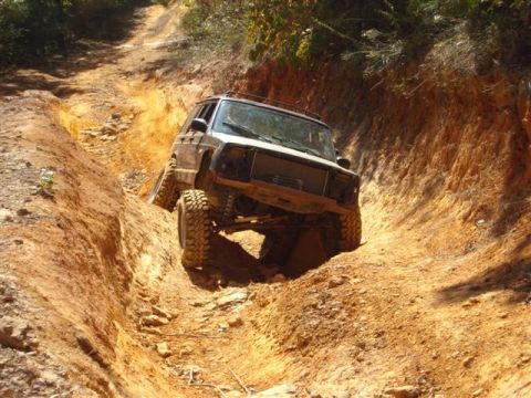 2008 International School Bus - Off-road Jeep Cherokee XJ tackling a challenging trail with steep inclines and deep ruts.