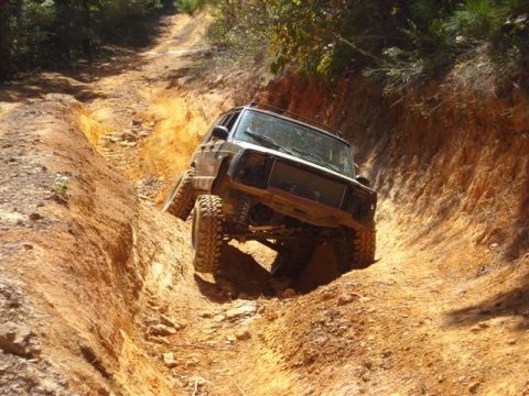 2008 International School Bus - This Jeep Cherokee is tackling a challenging off-road trail, with its tires digging into the loose dirt.