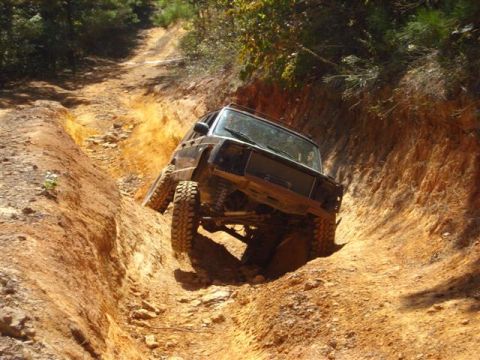 2008 International School Bus - An off-road SUV tackles a challenging, narrow dirt trail with steep, eroded sides.