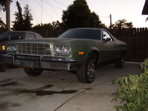 1973 Ford Ranchero - A green pickup truck with a chrome grille and bumper is parked outside.