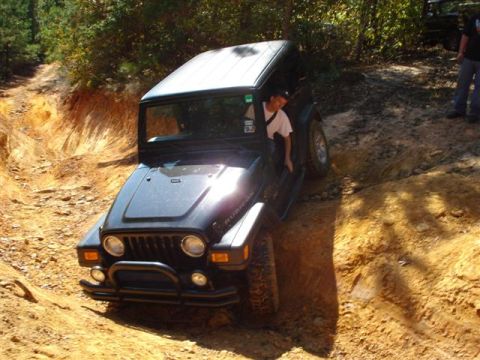 2008 International School Bus - A Jeep Wrangler navigates a challenging off-road trail with steep inclines and turns.