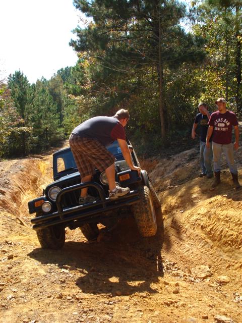 2008 International School Bus - Jeep Wrangler navigates a challenging off-road trail with friends watching.