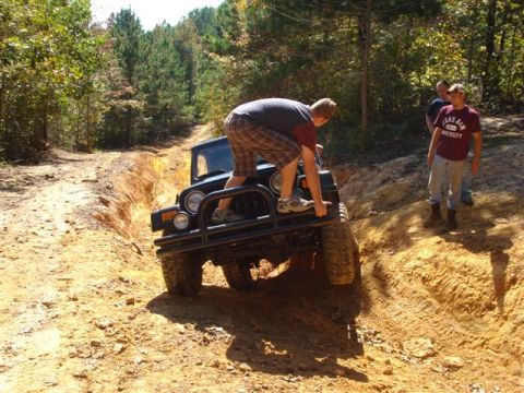 2008 International School Bus - A Jeep Wrangler is driven through a challenging off-road trail with onlookers present.