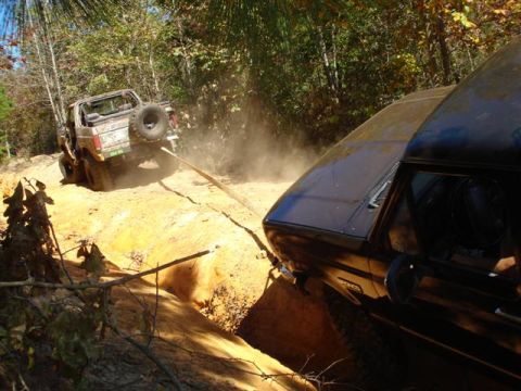 2008 International School Bus - Two off-road vehicles are stuck in the dirt, one being towed by the other with a tow strap.