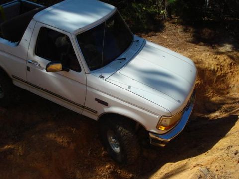 2008 International School Bus - White Ford Bronco navigating a steep dirt incline.