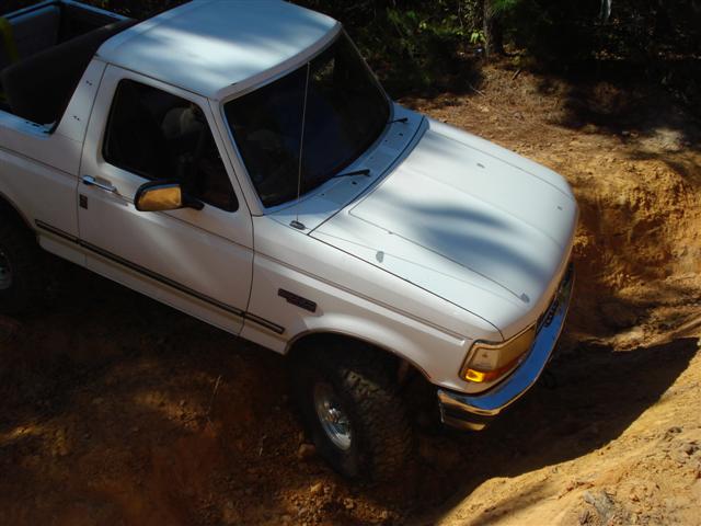 White Ford Bronco on a dirt trail, front quarter view
