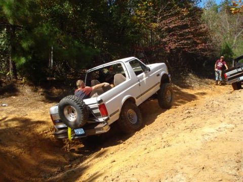 2008 International School Bus - A white Ford Bronco navigates a steep dirt trail with another vehicle visible in the background.