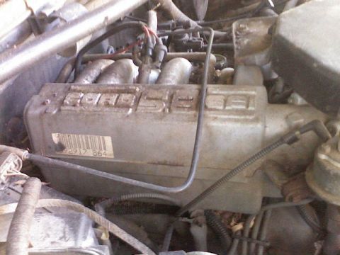 1994 Ford Bronco - Close-up of an engine valve cover with embossed lettering and a barcode sticker.
