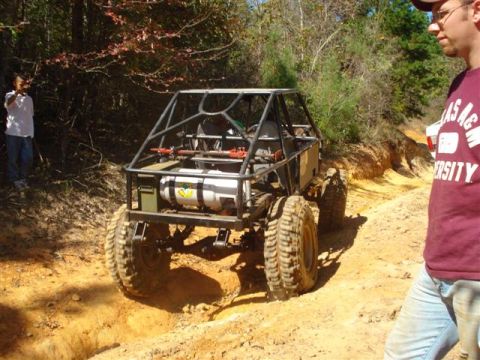2008 International School Bus - A custom-built off-road buggy navigates a challenging dirt path, with onlookers observing the action.
