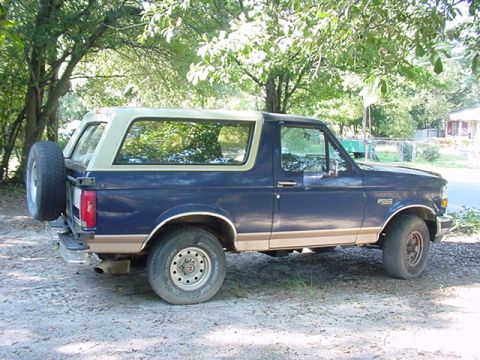 1994 Ford Bronco - This Ford Bronco is parked outside on a sunny day with trees in the background.