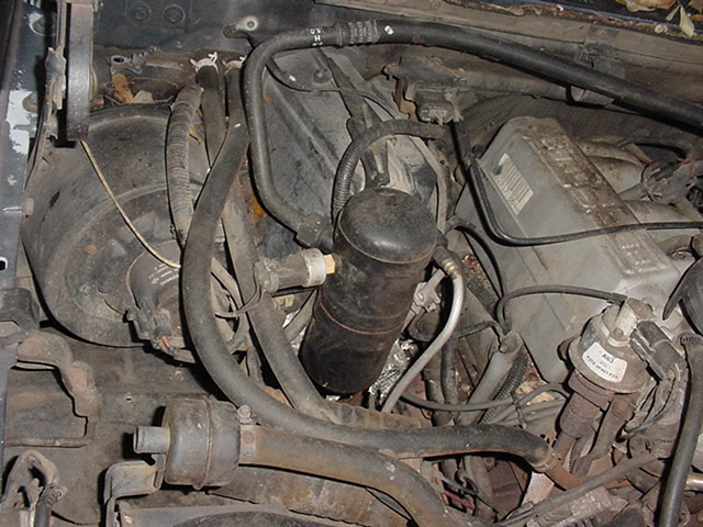 Engine bay showing AC accumulator, hoses, and electrical components