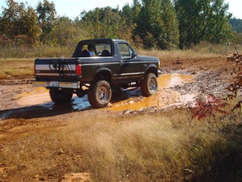 2008 International School Bus - Ford Bronco navigates a muddy trail during an off-road excursion.