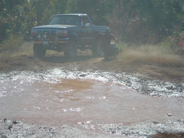 Pickup truck driving through mud with an ATV nearby