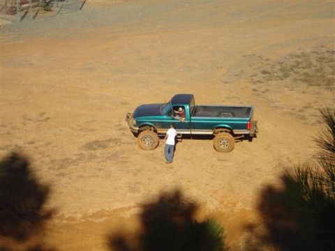 2008 International School Bus - A green pickup truck is parked on a dirt surface with two people nearby.