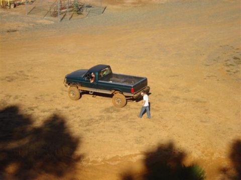 2008 International School Bus - A green pickup truck is seen from above on a dirt field, with a person walking next to it.