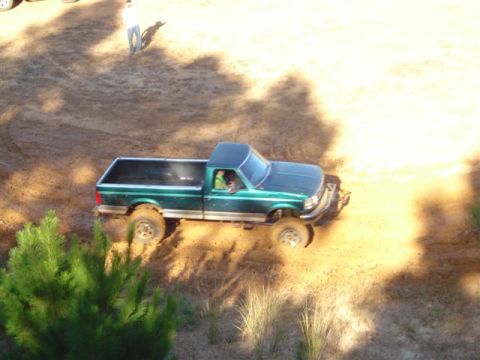 2008 International School Bus - Pickup truck navigating a dirt path with a person observing in the distance.