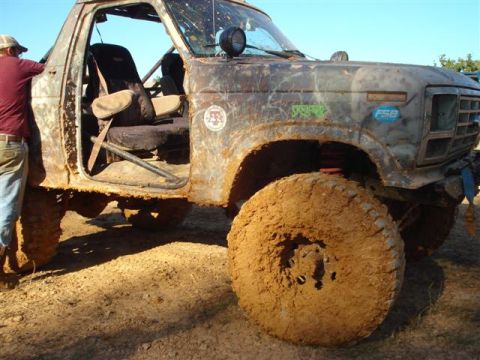 2008 International School Bus - This heavily modified off-road vehicle is covered in mud, obscuring its original make and model year.