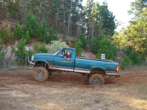 2008 International School Bus - A teal pickup truck navigates a muddy off-road course, with a 'KEEP OFF' sign visible in the background.