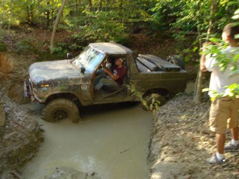 2008 International School Bus - This vintage pickup truck navigates a challenging muddy trail, with one person driving and another observing.