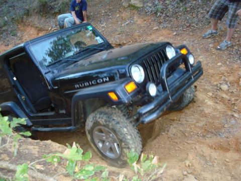 2008 International School Bus - A black Jeep Wrangler Rubicon navigates a challenging off-road trail, with two people observing.