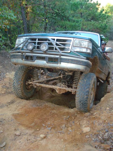 2008 International School Bus - A modified pickup truck is shown tackling a challenging off-road obstacle on a dirt path.