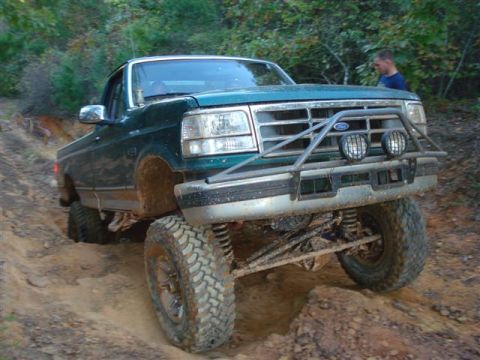 2008 International School Bus - Ford F-Series pickup truck tackling rough terrain on a wooded trail.