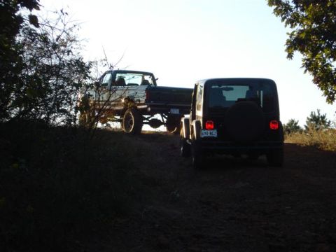 2008 International School Bus - Two off-road vehicles, a black Jeep and a pickup truck, navigate a dirt path under a bright sky.