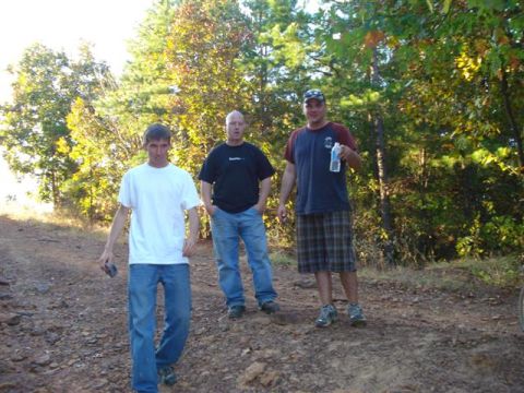 2008 International School Bus - Three men are on a dirt road in a wooded area with trees in the background.