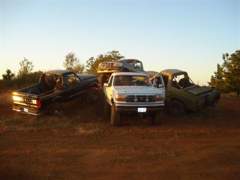 2008 International School Bus - Multiple trucks parked on a dirt hill at sunset.