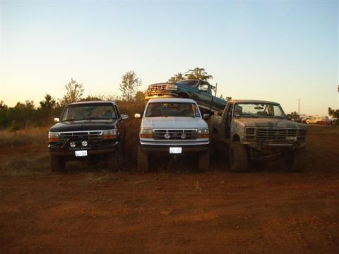 2008 International School Bus - Several trucks and a school bus are parked on a dirt incline under a clear sky.