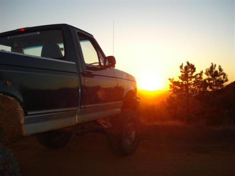 2008 International School Bus - Pickup truck parked on dirt with sunset in background.