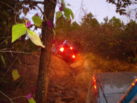 2008 International School Bus - Two vehicles navigate a challenging off-road trail, with one vehicle's brake lights glowing brightly.
