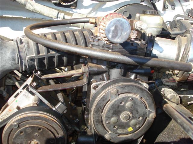 Engine compartment with air intake hose, compressor, and other engine parts visible